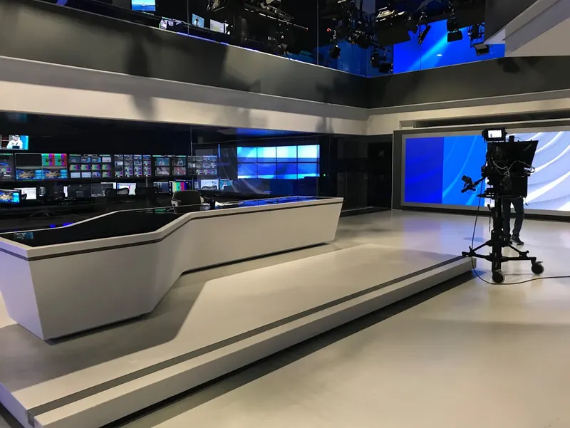 Al Araby TV's news desk at Park Royal, with a studio camera beside it and the production gallery visible behind a glass wall.