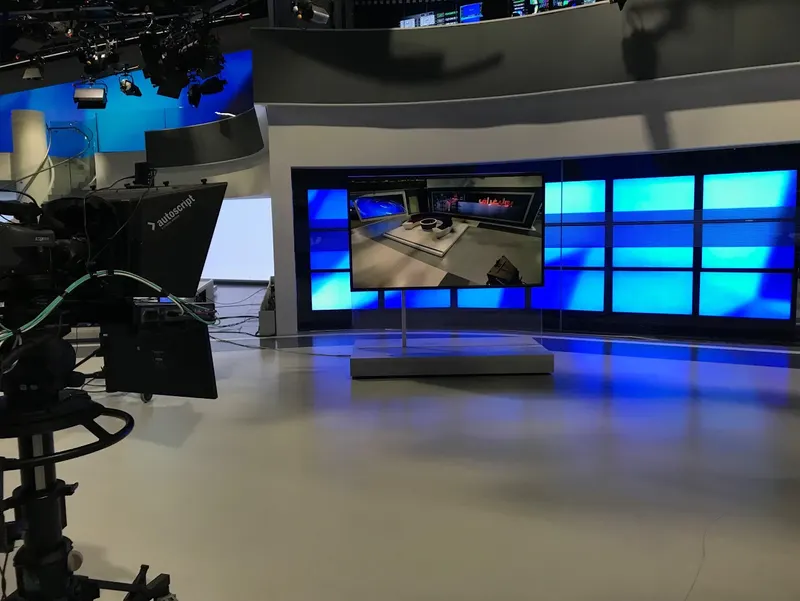 The large touchscreen used for weather and interactive news segments in Al Araby TV's Park Royal studio, standing in front of a blue video wall.