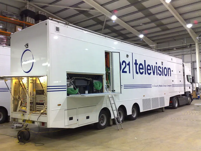 O21 Television's Unit 7 outside broadcast truck during fit-out, with its rear and side equipment hatches open to show patch bays and cable looms.