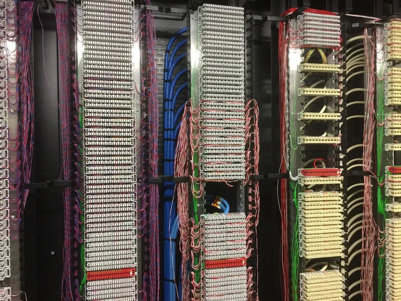 Punch-down frames in IMG's Stockley Park data centre, dense with neatly dressed jumper wiring and blue network cable looms.