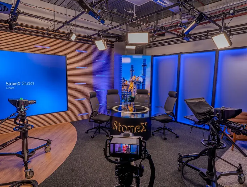 StoneX's London studio, with a round presenter table, cameras on pedestals and a video wall showing the StoneX Studios logo.