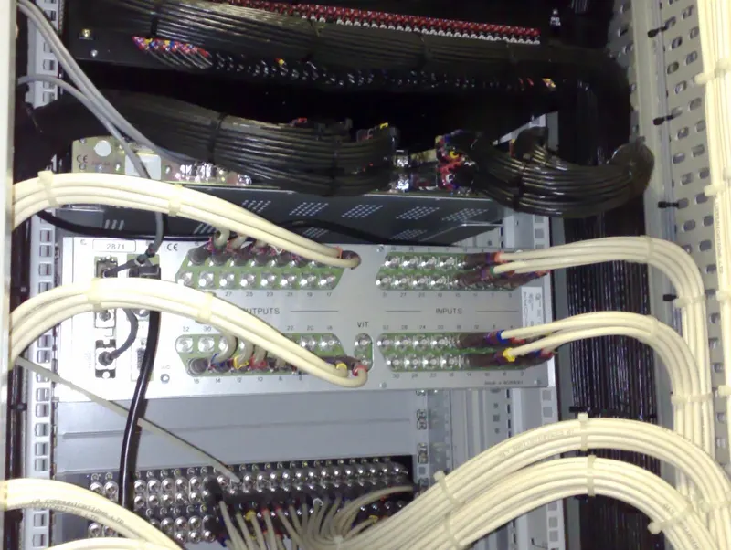 Cream coax looms dressed into the inputs and outputs of a router panel in Virgin Media's Knowsley headend, with black multicore looms above.