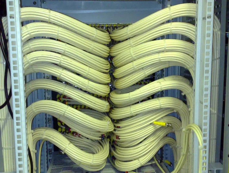 The rear of a rack in Virgin Media's Knowsley headend, with cream coax looms dressed in matching loops on each side.